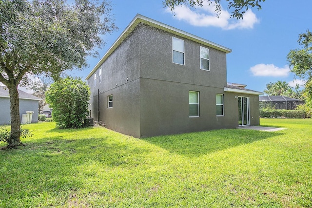 rear view of house with a lawn, cooling unit, and stucco siding