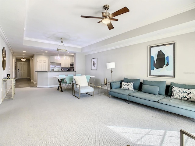 carpeted living room featuring crown molding, ceiling fan, and a raised ceiling