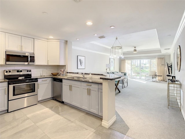 kitchen featuring appliances with stainless steel finishes, light carpet, stone countertops, kitchen peninsula, and tasteful backsplash