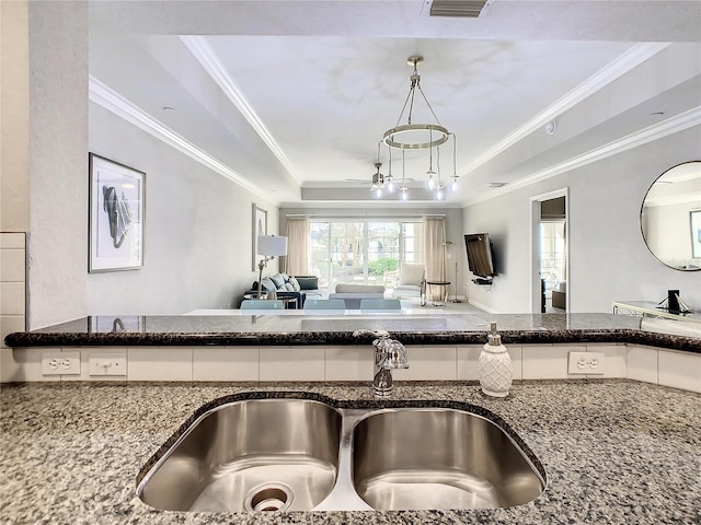 kitchen with white cabinetry, dark stone counters, a tray ceiling, and a sink