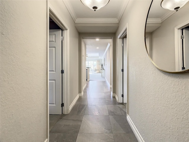 hallway featuring baseboards, a textured wall, and ornamental molding