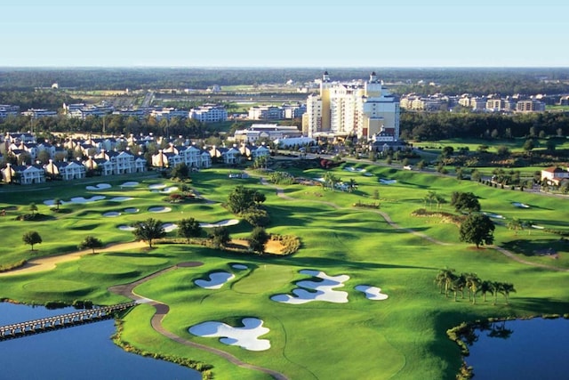 drone / aerial view featuring a city view, golf course view, and a water view