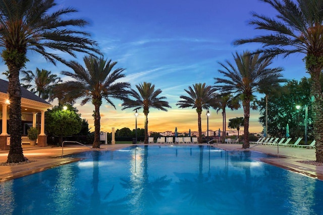 pool at dusk featuring a patio