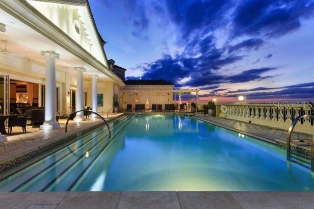 pool at dusk with a patio area