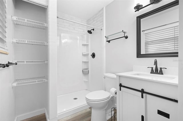 bathroom with a shower, hardwood / wood-style floors, toilet, and vanity