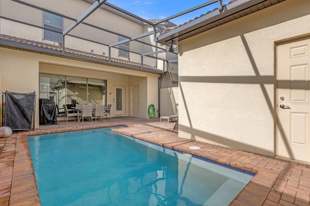 view of swimming pool featuring glass enclosure and a patio area