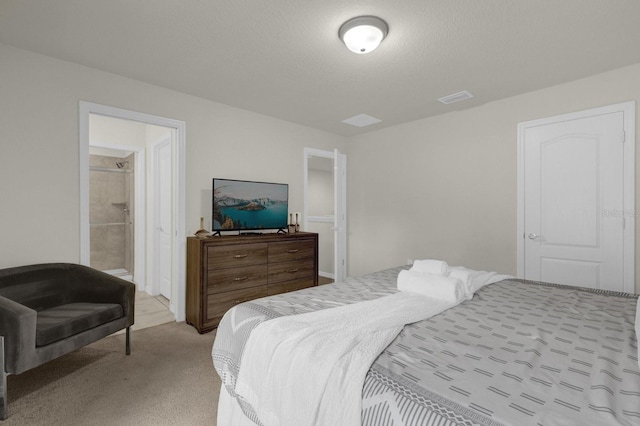 bedroom featuring a textured ceiling, light carpet, and ensuite bath