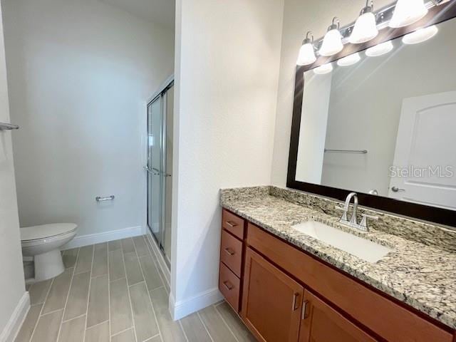 bathroom with toilet, a shower with door, and vanity