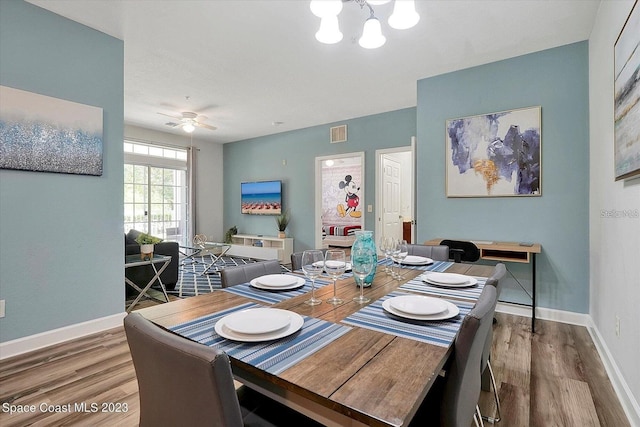 dining space with hardwood / wood-style floors and ceiling fan with notable chandelier