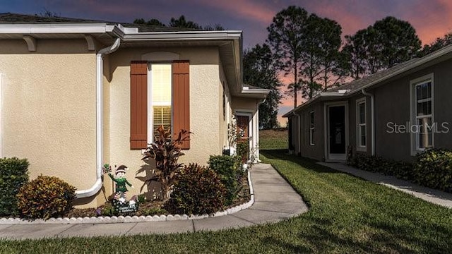 view of side of home featuring a lawn and stucco siding