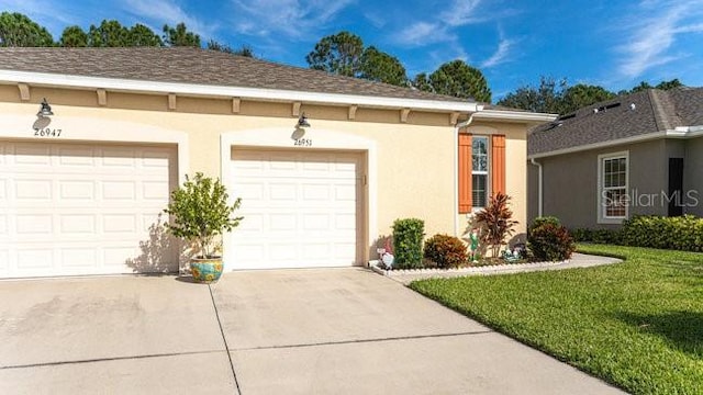 exterior space with a garage, a front yard, driveway, and stucco siding