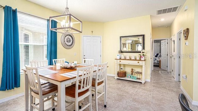 dining space featuring light tile patterned floors, baseboards, visible vents, and a notable chandelier