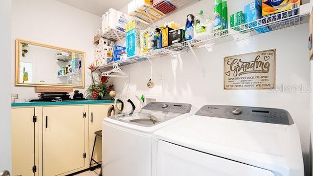 clothes washing area featuring separate washer and dryer and cabinet space