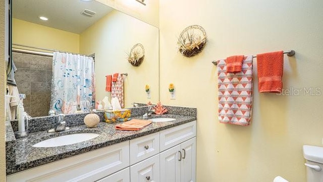 full bath with double vanity, a sink, toilet, and a shower with curtain