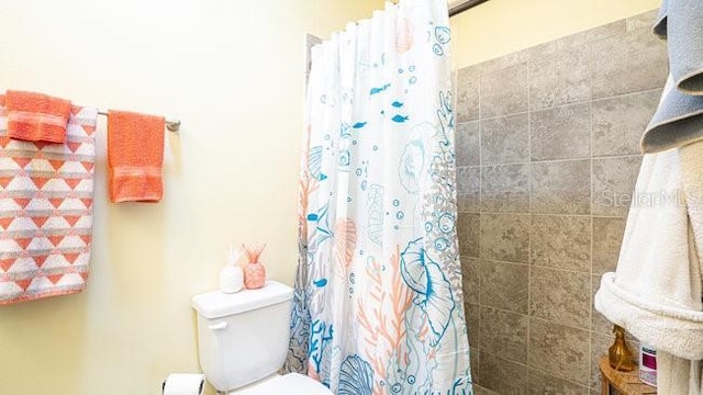 full bath with tiled shower and toilet