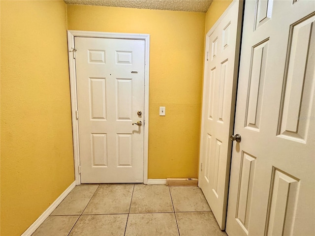 doorway to outside with a textured ceiling and light tile patterned flooring