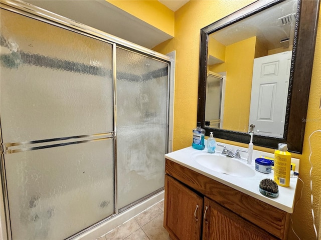 bathroom with tile patterned flooring, a shower with shower door, and vanity