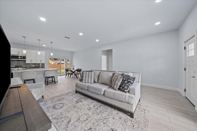 living room with light wood-type flooring, plenty of natural light, and sink