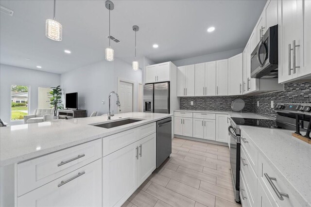 kitchen with white cabinets, light stone countertops, stainless steel appliances, and sink