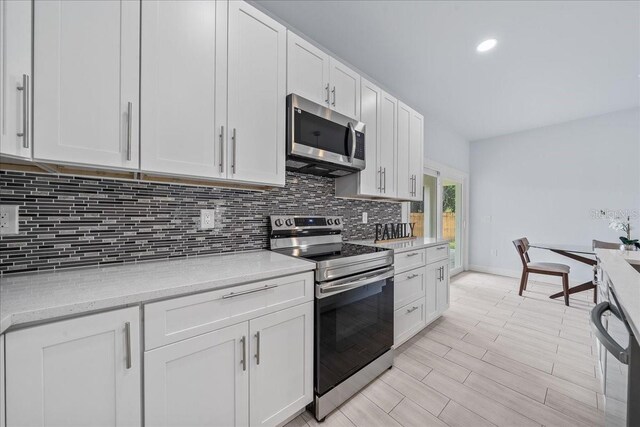 kitchen featuring white cabinetry, light hardwood / wood-style flooring, backsplash, and stainless steel appliances