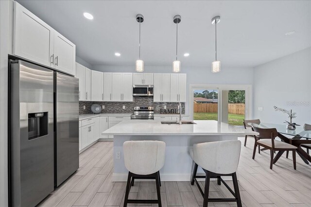 kitchen with light hardwood / wood-style flooring, sink, appliances with stainless steel finishes, and white cabinetry