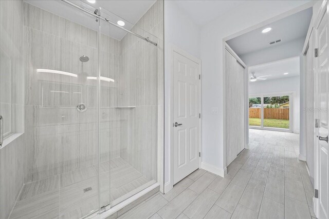 bathroom with ceiling fan and a shower with shower door