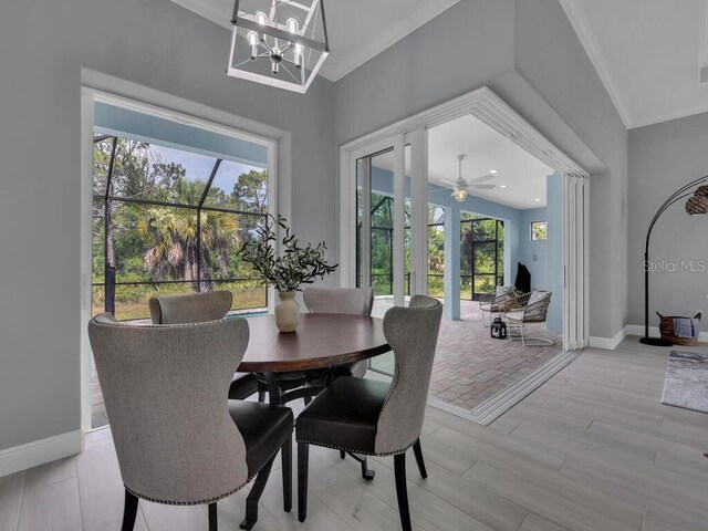 dining space featuring a wealth of natural light, ornamental molding, ceiling fan with notable chandelier, and light hardwood / wood-style floors