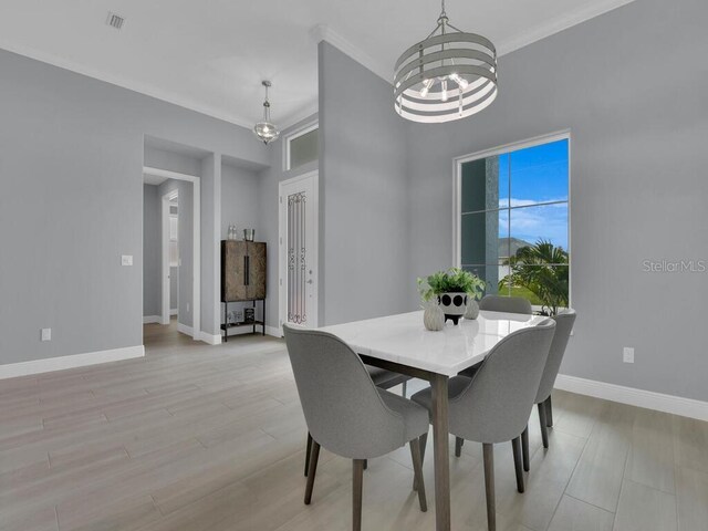 dining space with ornamental molding, light wood-type flooring, and a chandelier