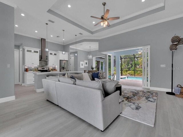 living room with ornamental molding, a raised ceiling, and ceiling fan