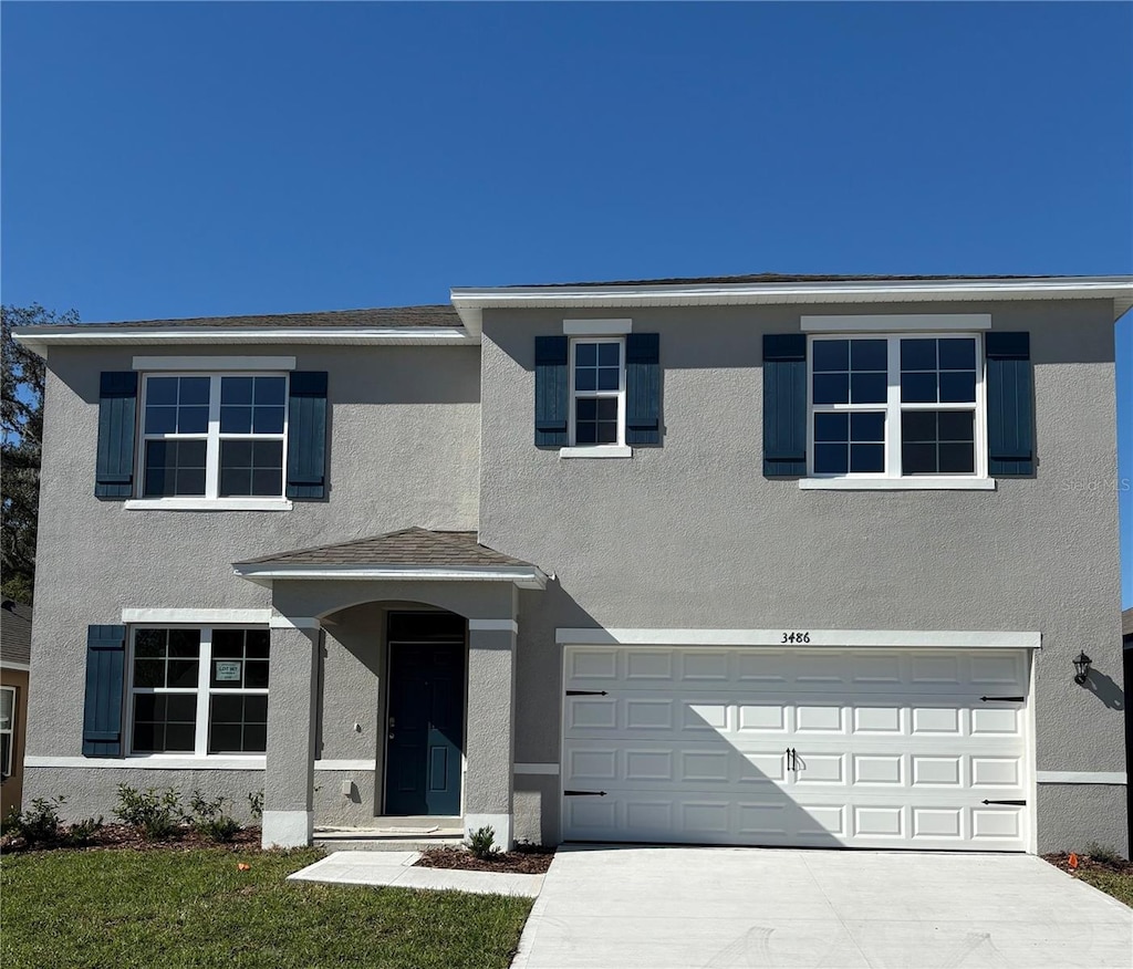 traditional-style house with concrete driveway, an attached garage, and stucco siding