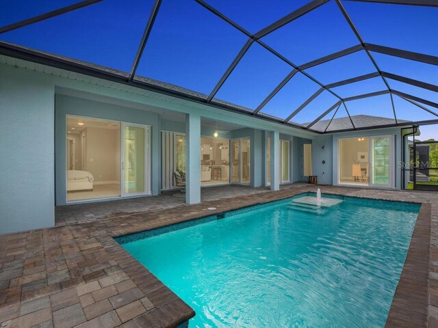 view of pool with glass enclosure and a patio