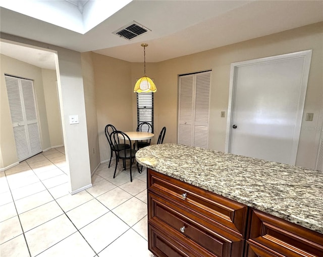 kitchen with light tile patterned floors, light stone counters, and decorative light fixtures