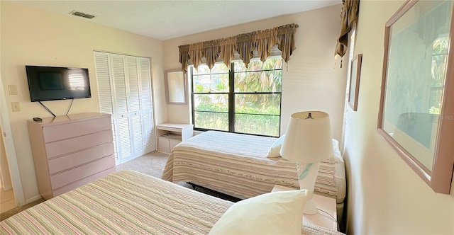 bedroom featuring a closet, light colored carpet, and a textured ceiling