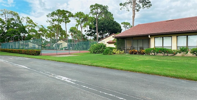 view of tennis court featuring a lawn