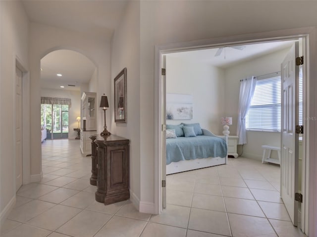 hall with arched walkways, light tile patterned floors, and baseboards