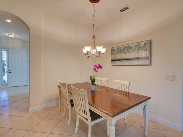 dining area with light tile patterned floors, baseboards, visible vents, arched walkways, and a chandelier