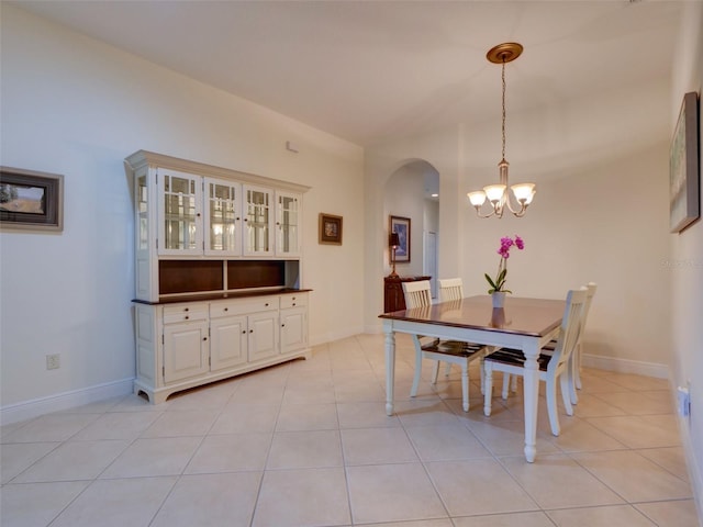 dining area featuring an inviting chandelier, light tile patterned floors, baseboards, and arched walkways