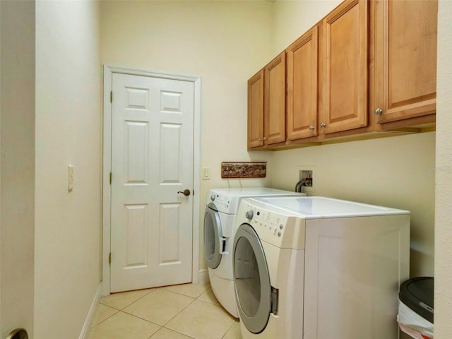 clothes washing area with light tile patterned floors, cabinets, and washing machine and dryer