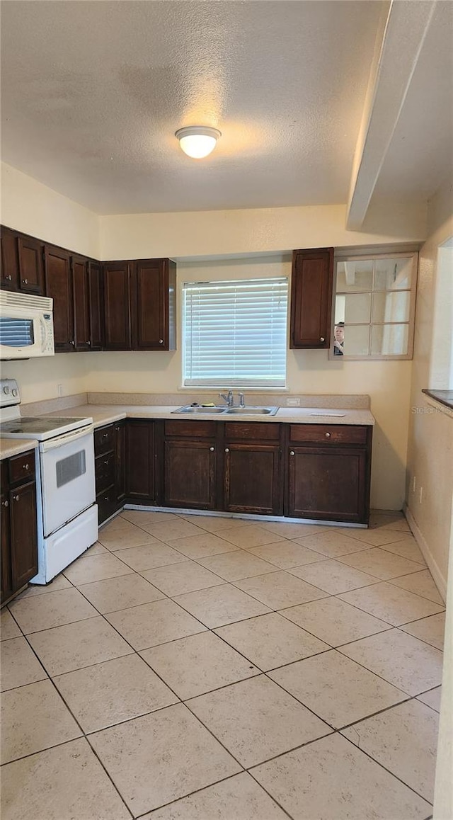 kitchen with a textured ceiling, dark brown cabinets, sink, and white appliances