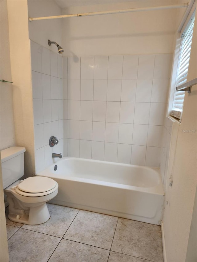 bathroom with tile patterned flooring, toilet, and tiled shower / bath