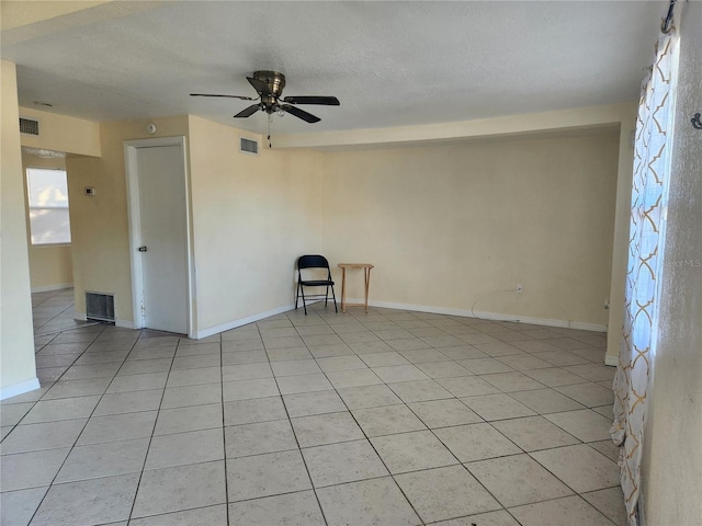 spare room featuring ceiling fan, light tile patterned floors, and a textured ceiling