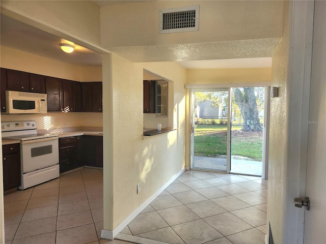 kitchen featuring dark brown cabinets, white appliances, and light tile patterned floors