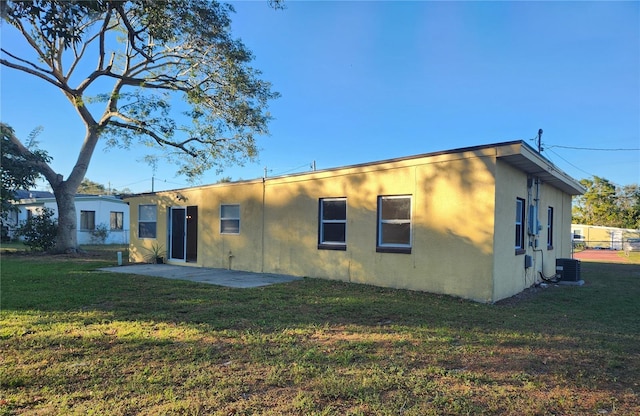 rear view of house with a yard, cooling unit, and a patio