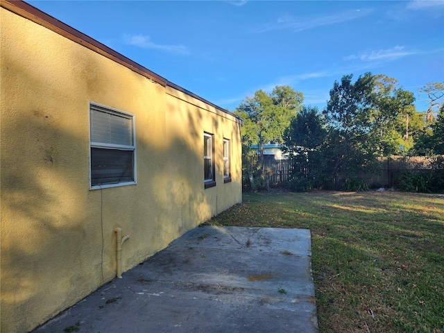 view of side of home featuring a lawn and a patio area