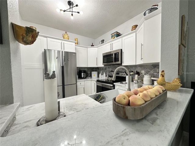 kitchen featuring white cabinetry, tasteful backsplash, kitchen peninsula, stainless steel appliances, and a textured ceiling