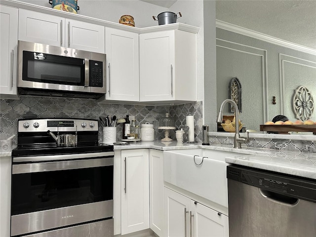 kitchen with light stone counters, white cabinets, stainless steel appliances, and decorative backsplash