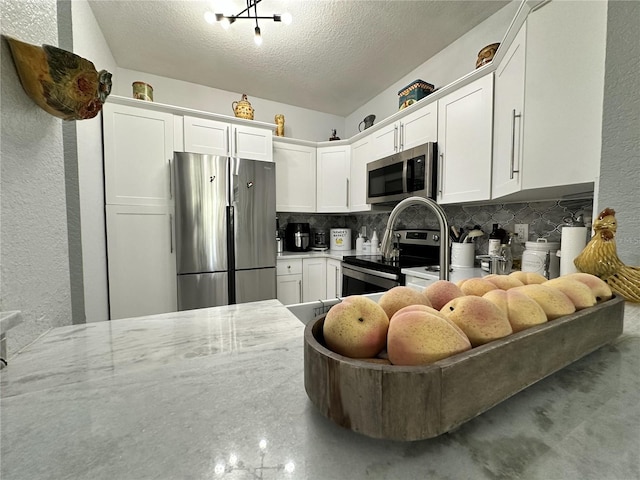 kitchen featuring stainless steel appliances, white cabinets, and a textured ceiling