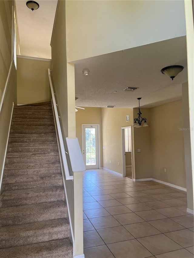 staircase featuring a textured ceiling, a chandelier, and tile patterned floors