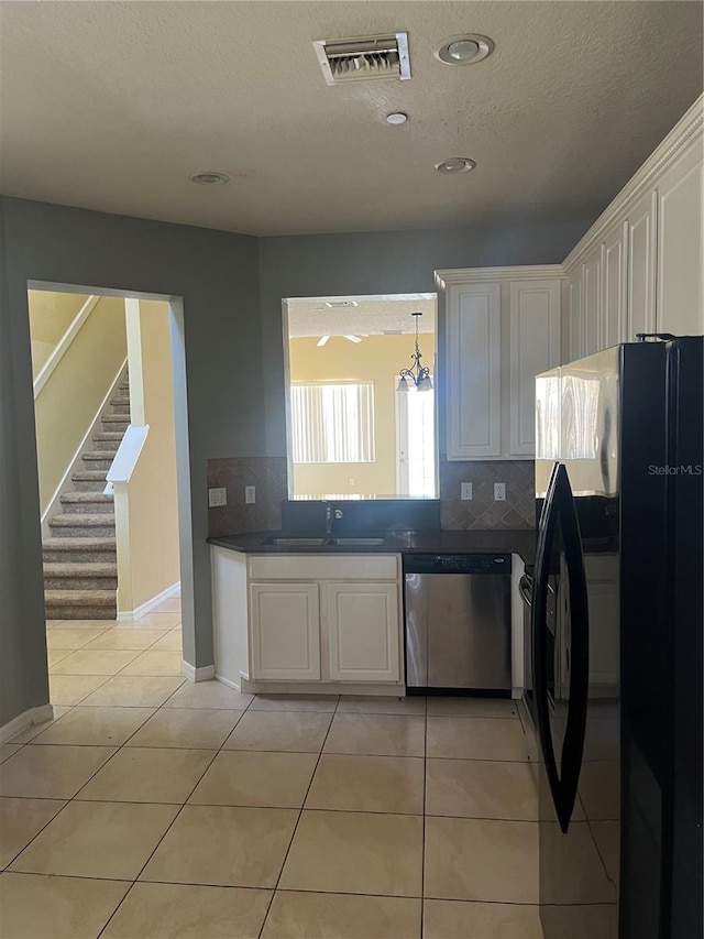 kitchen with dishwasher, white cabinetry, light tile patterned flooring, black fridge, and tasteful backsplash