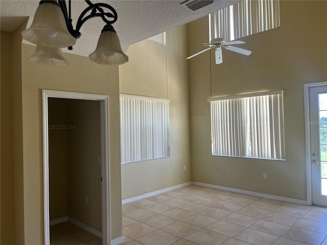 unfurnished bedroom featuring light tile patterned floors, a high ceiling, a closet, and a textured ceiling